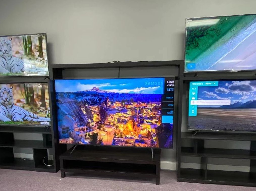Multiple TVs display vibrant nature and landscape scenes in a showroom.