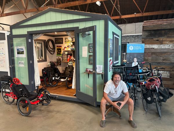 Man sitting on a stool in a bike shop with recumbent bikes.