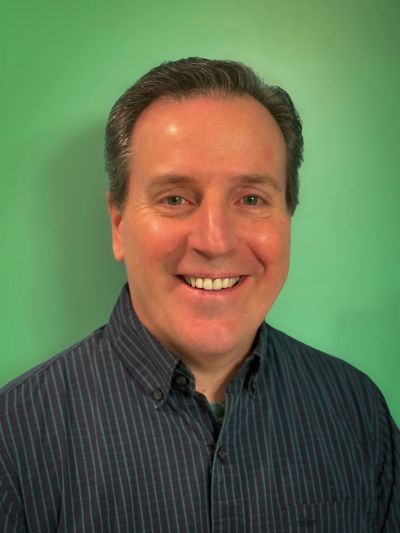 Man smiling against a green background.