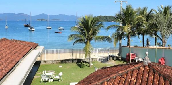 Coastal view with boats, palm trees, and tiled rooftops under a clear blue sky.