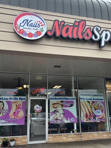Nail spa storefront with promotional posters and open sign.
