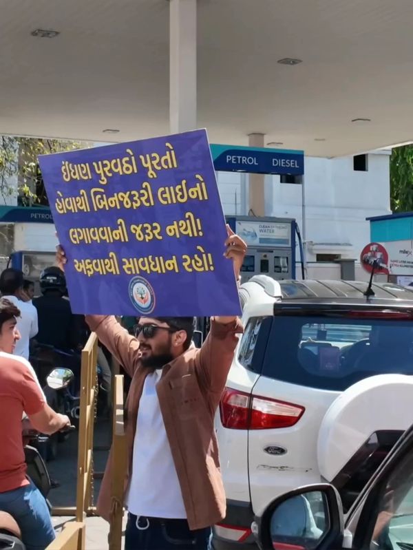 Man holding a caution sign at a fuel station.