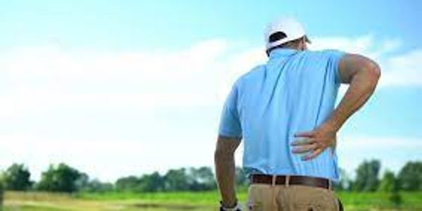 Golfer holding his lower back in pain on the course.