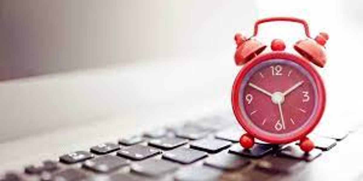Red alarm clock on a laptop keyboard.