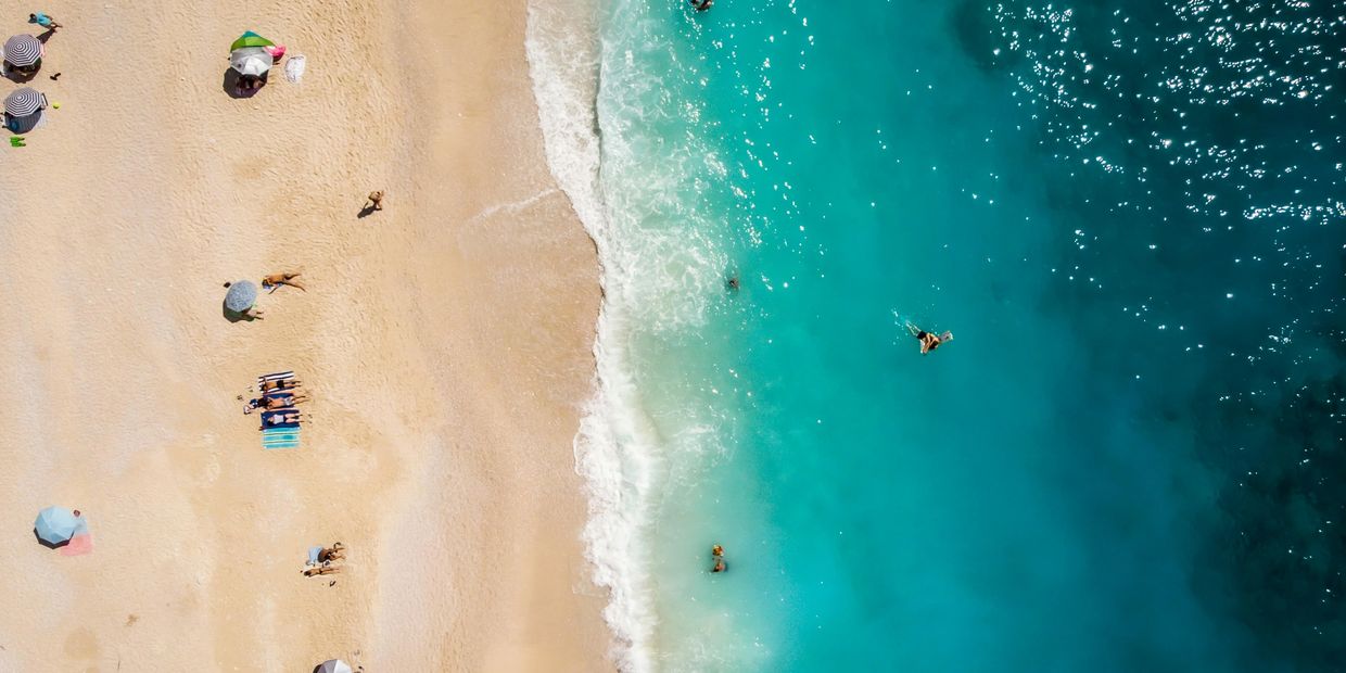 Overhead view of people on a beach and in the water.