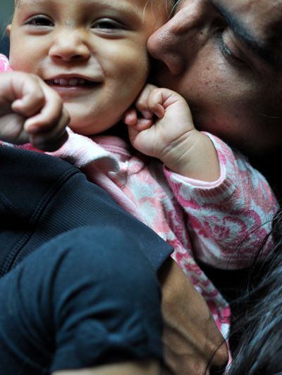 A tender moment of a parent kissing a smiling baby.