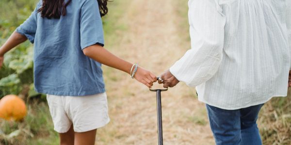 Two people holding hands while walking outside on a path.