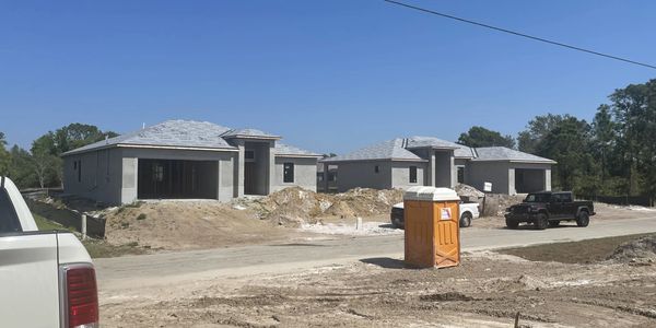 Two single-story houses under construction on a sunny day.