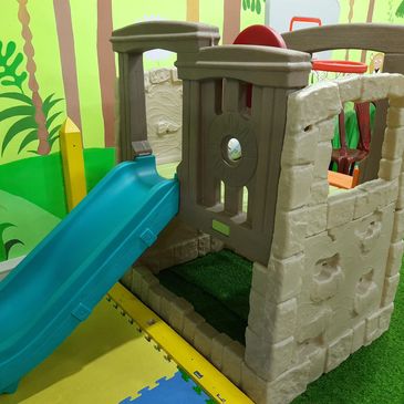 Indoor children's play area with a small slide and colorful wall murals.