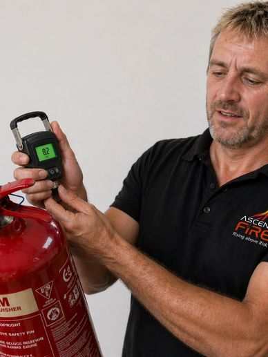 Man inspecting a fire extinguisher with a digital gauge.