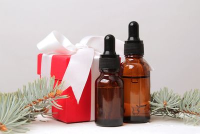 Two amber dropper bottles with a red gift box and pine branches.