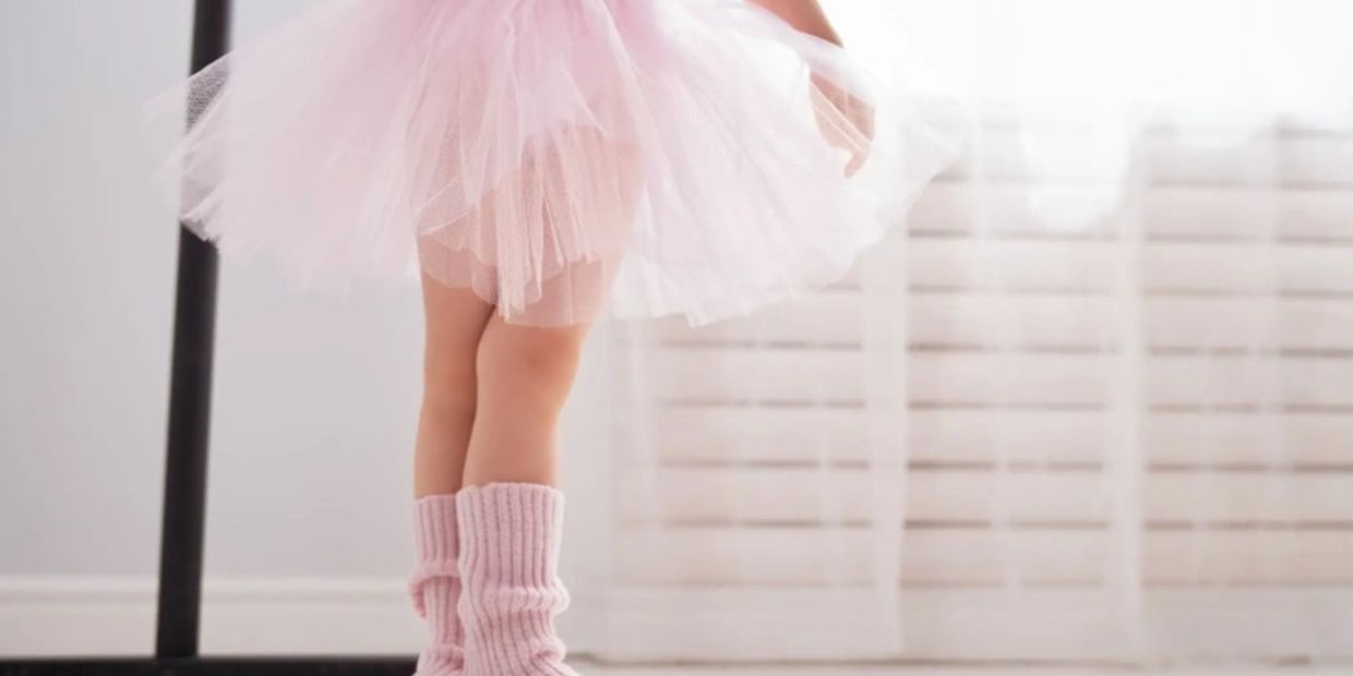 Child in pink tutu and leg warmers dancing.