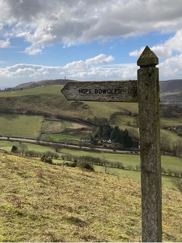 Rustic wooden signpost pointing to Hope Bowdler.