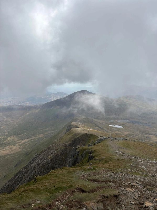 Foggy mountain ridge under a cloudy sky.