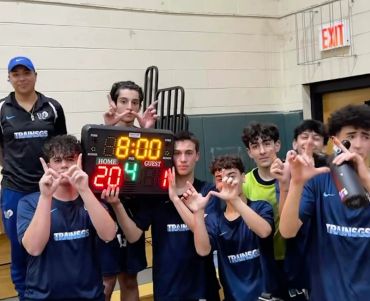 Youth basketball team posing with final game scoreboard showing 20-14.