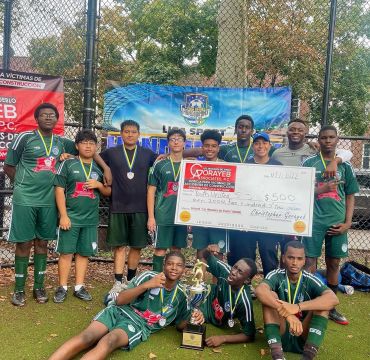Youth soccer team celebrating win with trophy and oversized check.