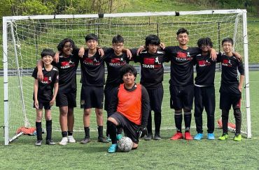 Youth soccer team posing together in front of goalpost on a field.