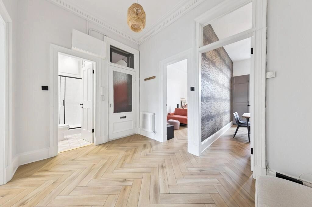 Bright hallway with wooden herringbone flooring and multiple doors.