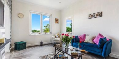 Bright, cozy living room with blue sofa and flowers.