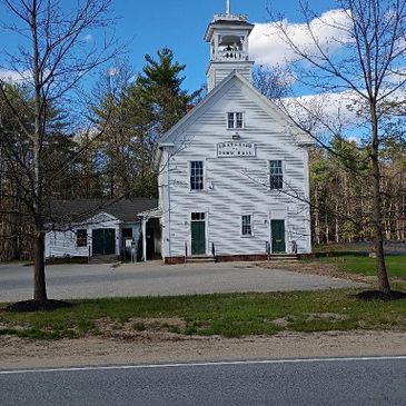 Historic white town hall building with a bell tower under a blue sky.