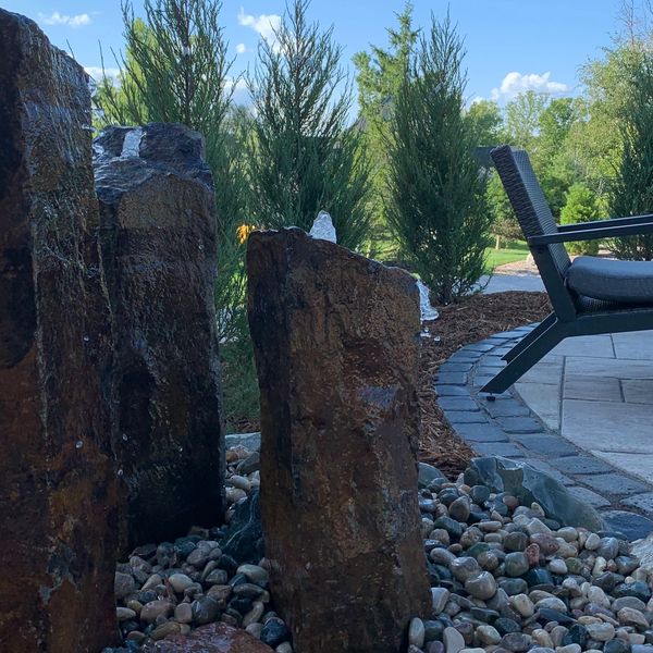 Basalt fountain beside paver patio and fire pit. 