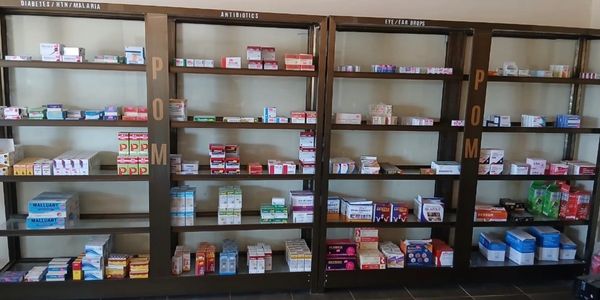 Shelves stocked with various medicines categorized by type in a pharmacy.