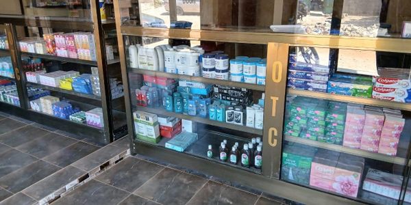 Glass shelves filled with OTC medicines and hygiene products in a pharmacy.