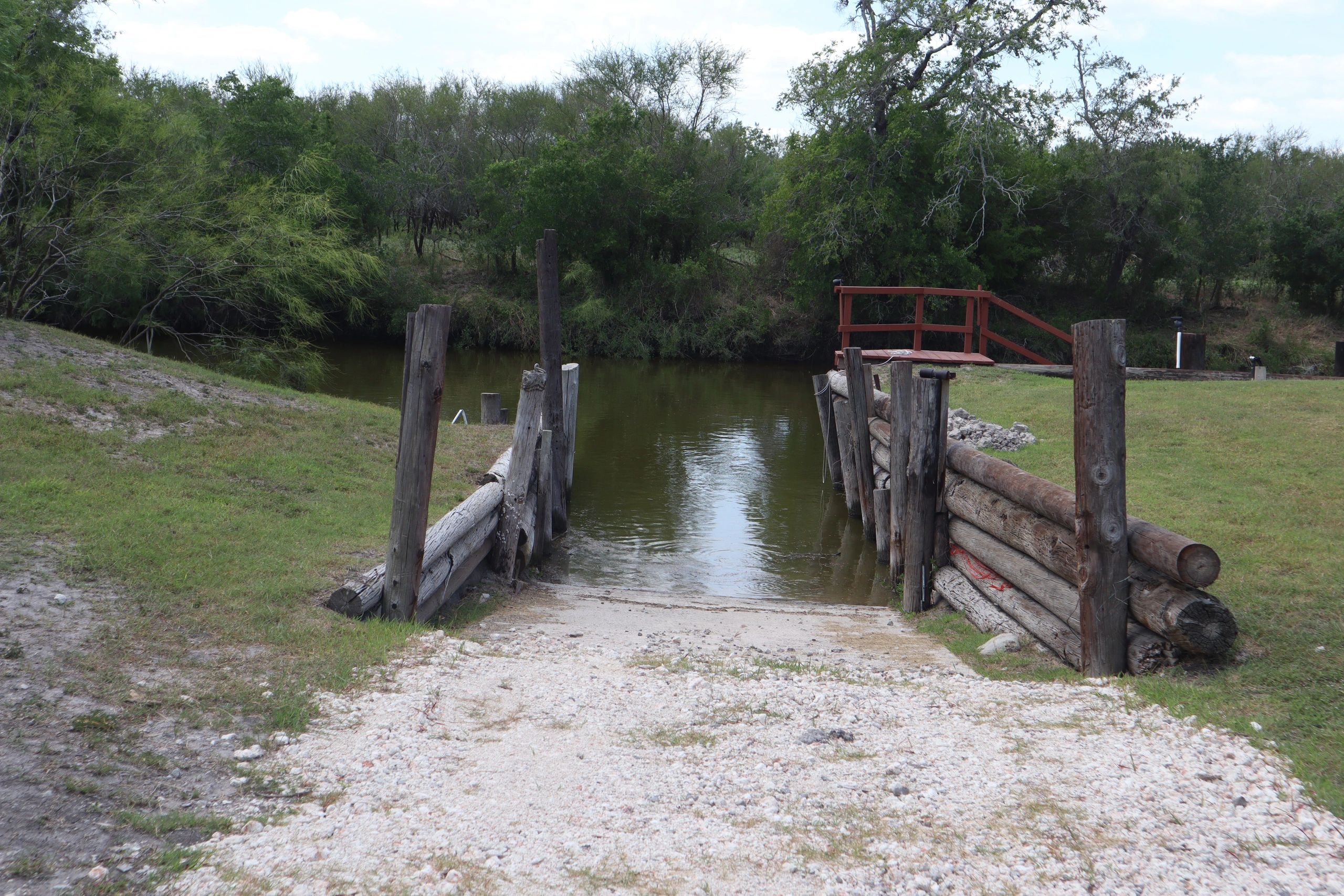 A small wooden dock on a river with greenery.