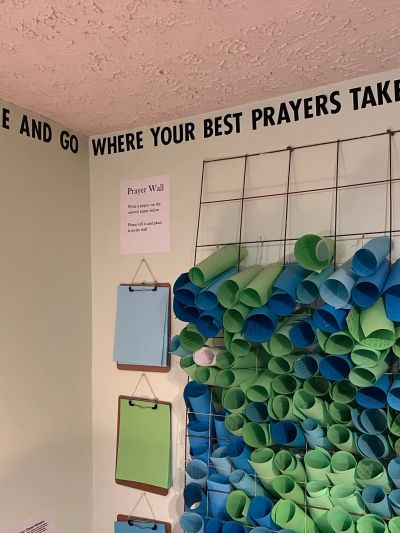 Colorful rolled papers arranged on a wire grid with inspirational text above.