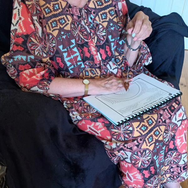 A person holding a pendulum over a chart.