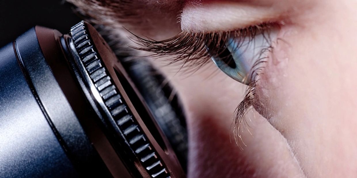 closeup image of an eye peering through a microscope