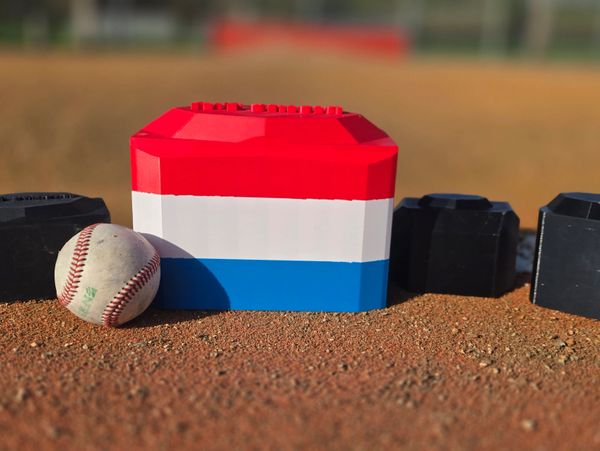 A baseball and colorful blocks on a dirt field.