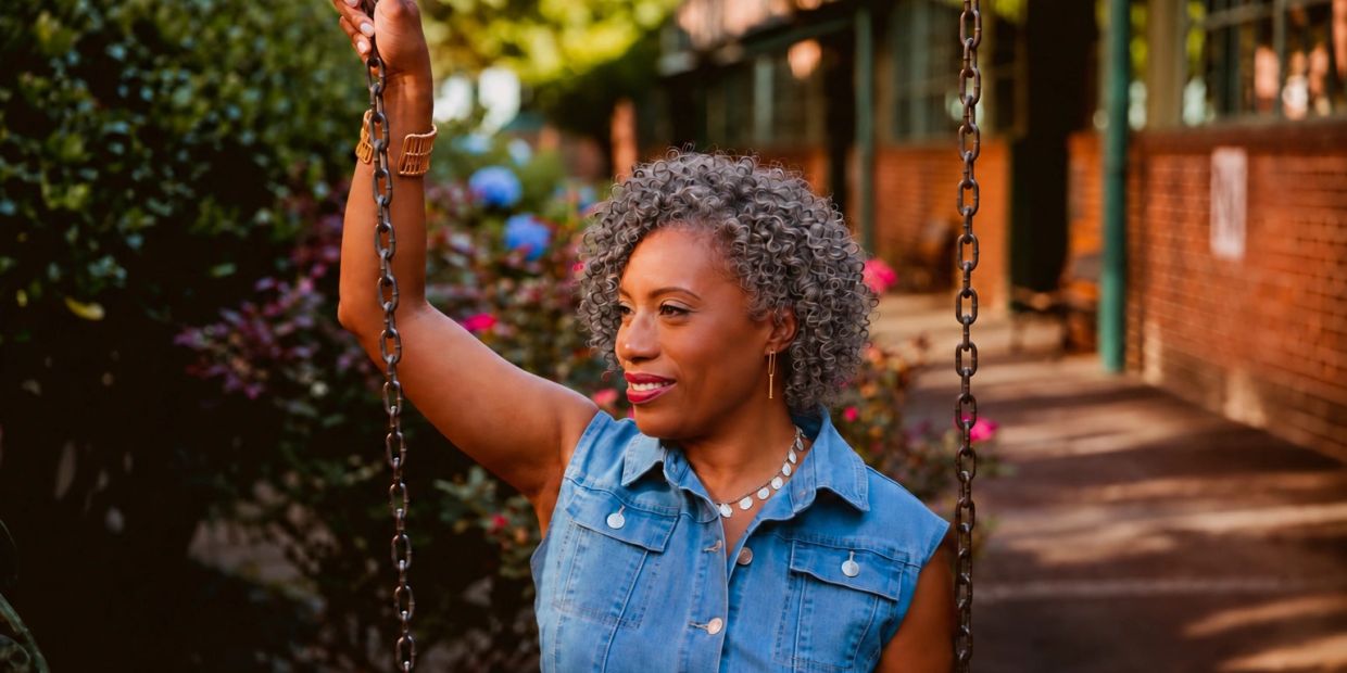 Woman with curly gray hair holding a swing chain outdoors.