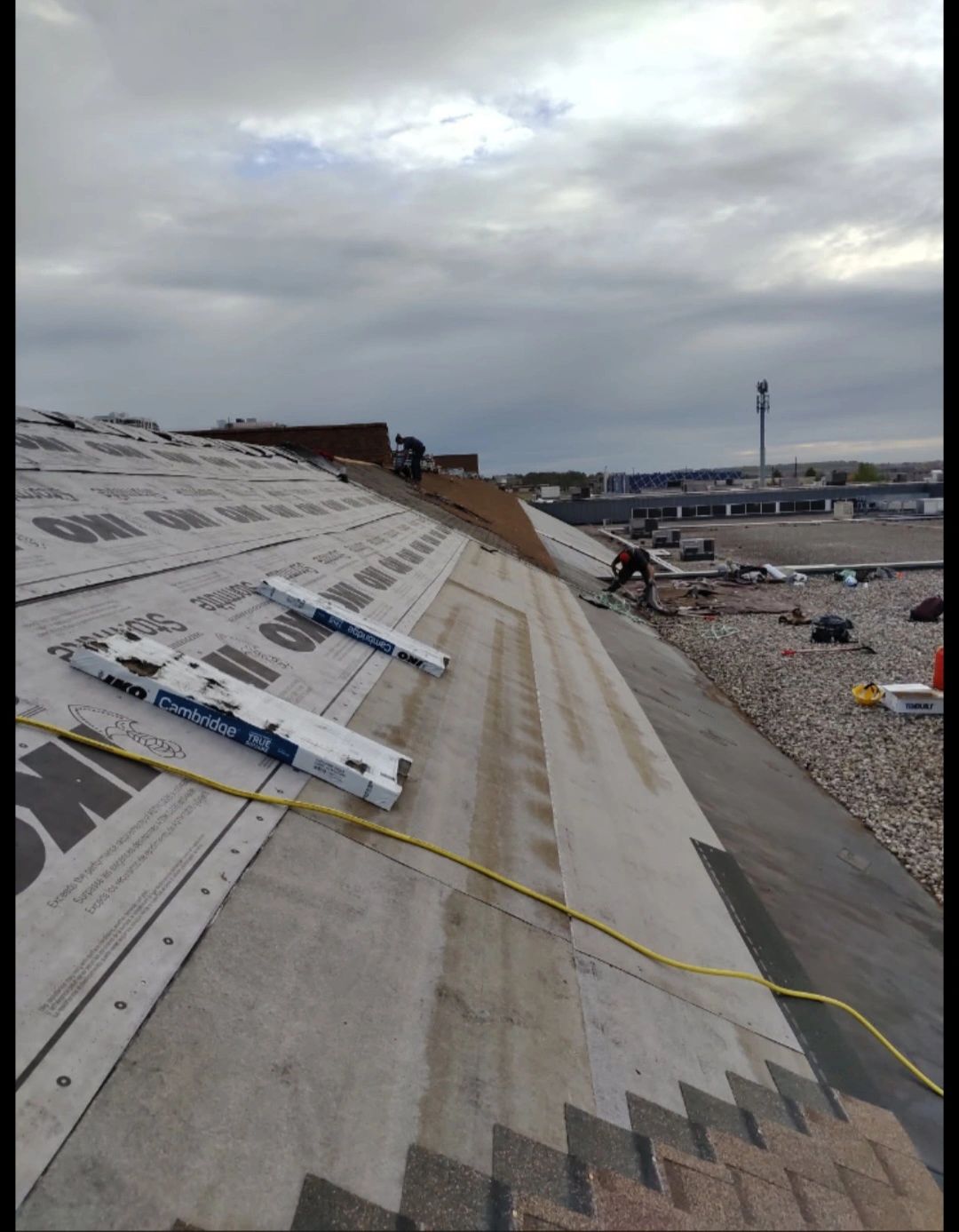 Workers shingling large roof