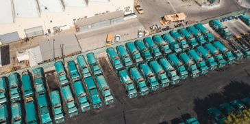 Aerial view of many green trucks parked in organized rows at a depot.