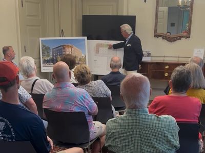 A man presenting architectural plans to an audience.