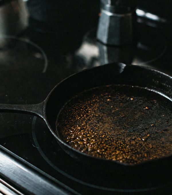 Cast iron skillet with oil heating on a stovetop.