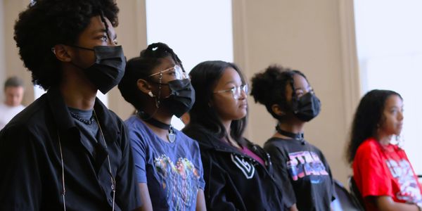 Group of young people wearing masks and sitting indoors.