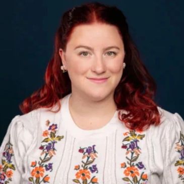 Woman with red hair and floral sweater.