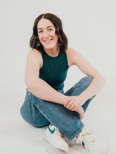Young woman sitting cross-legged, smiling.
