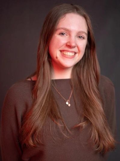 Young woman smiling with long hair and necklace.