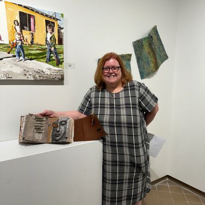 Woman smiling beside unique art pieces in a gallery.
