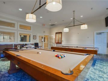 A room with two pool tables and hanging lights.