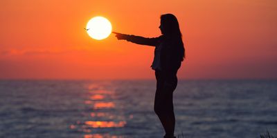 Silhouette of a woman pointing at a sunset