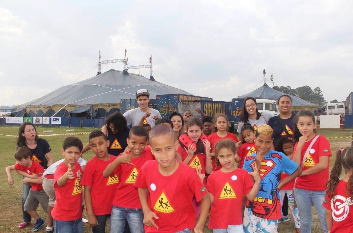 Children and adults posing outdoors near a circus tent.