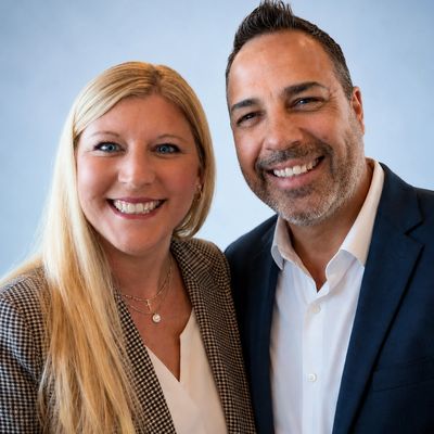Smiling man and woman posing together in business attire.