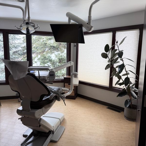 Modern dental office with a dental chair, equipment, and large windows.