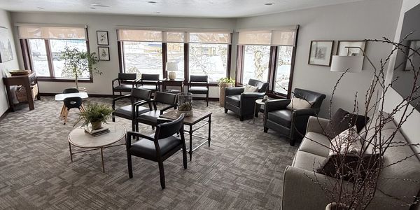 A modern, cozy waiting room with black chairs and large windows.