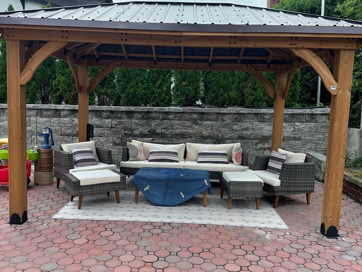 Outdoor patio set under a wooden gazebo on red and gray hexagonal paving stones.