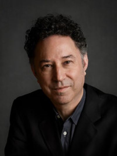 Portrait of a man with curly hair in a dark blazer.